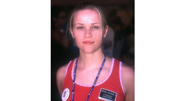 Reese Witherspoon trägt ein rotes Top mit der Aufschrift „Kids + Guns = A Deadly Equation“.