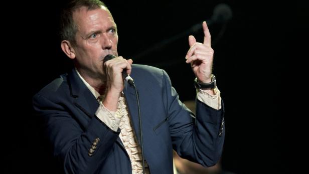 Hugh Laurie singt mit erhobenem Zeigefinger in ein Mikrofon.