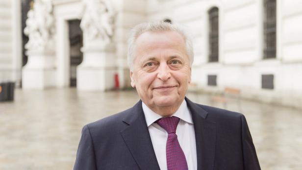 Ein älterer Mann mit Anzug und Krawatte lächelt in die Kamera.