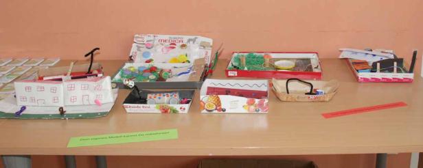 Auf einem Tisch stehen mehrere selbstgebastelte Modelle in Kartons.