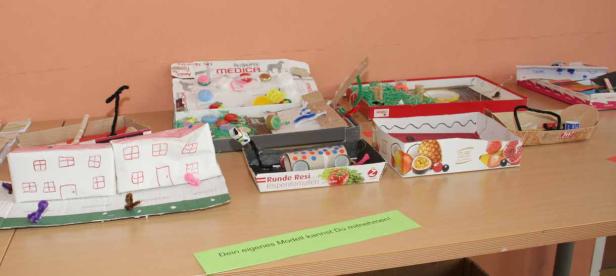 Auf einem Tisch stehen verschiedene Modelle, die aus Kartons und anderen Materialien gebastelt wurden.