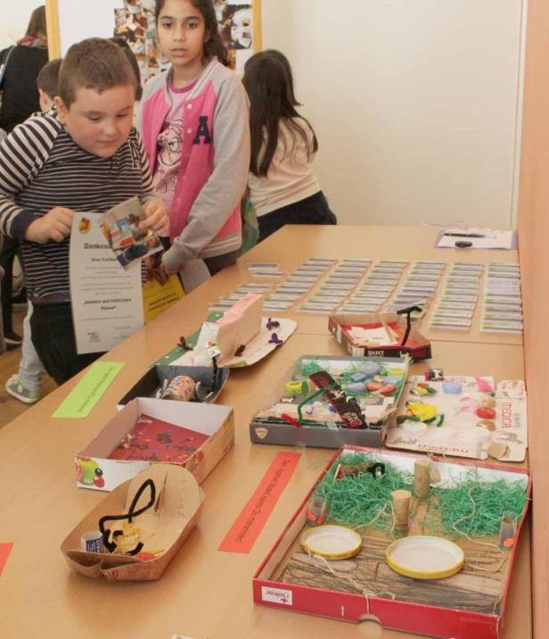 Kinder betrachten und präsentieren ihre selbstgebastelten Modelle in Schuhkartons.
