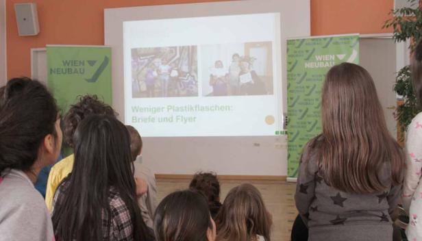 Kinder schauen auf eine Präsentation über die Reduzierung von Plastikflaschen.