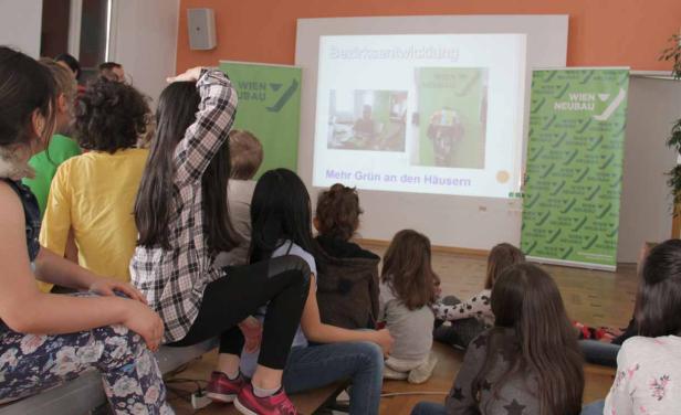 Eine Gruppe von Kindern schaut sich eine Präsentation über Bezirksentwicklung an.