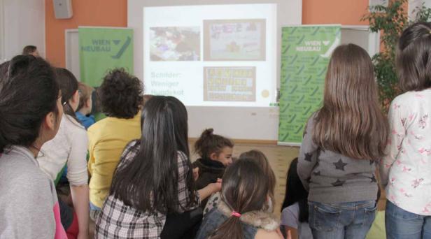 Eine Gruppe von Kindern schaut auf eine Präsentation zum Thema „Weniger Hundekot“.
