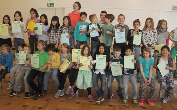 Eine Gruppe von Kindern und eine Frau halten Urkunden in den Händen.