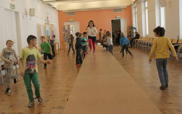 Eine Gruppe Kinder spielt in einem Raum mit einem improvisierten Laufsteg.