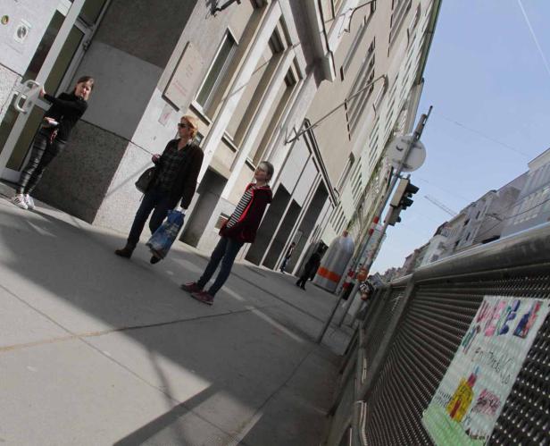 Drei Personen gehen an einem sonnigen Tag die Straße entlang.