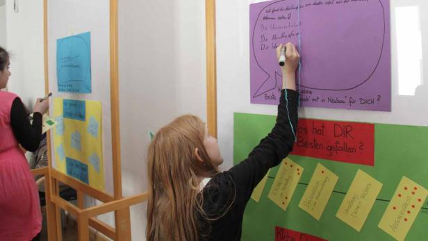 Ein Mädchen schreibt auf ein lila Plakat während einer Brainstorming-Sitzung.