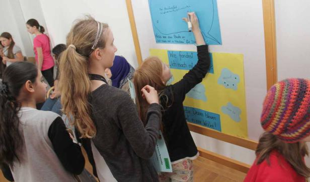 Eine Gruppe von Kindern beteiligt sich an einer interaktiven Aktivität mit Postern.