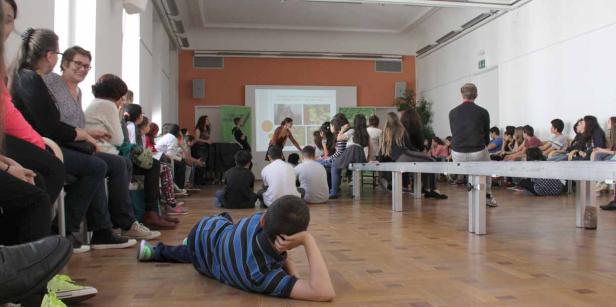 Eine Gruppe von Schülern sitzt während einer Präsentation in einem Klassenzimmer.