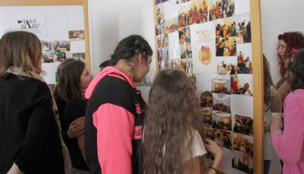 Eine Gruppe von Menschen betrachtet eine Fotocollage an einer Wand.