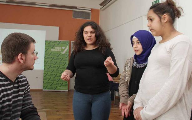 Eine Gruppe von Jugendlichen steht in einem Raum und diskutiert.