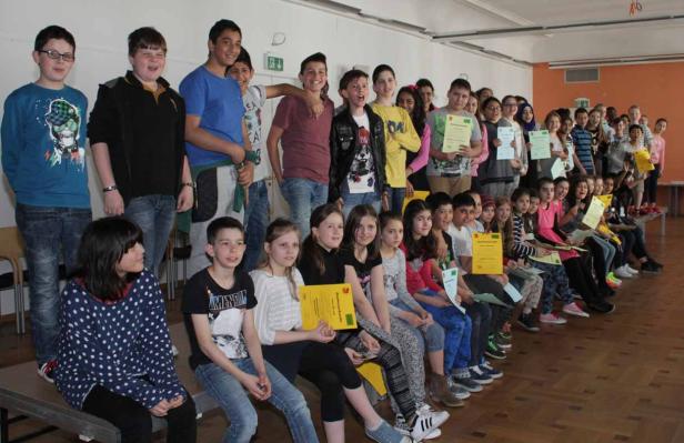 Eine Gruppe von Schülern sitzt und steht mit ihren Urkunden in einem Raum.