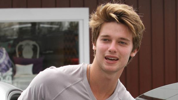 Ein junger Mann mit blonden Haaren und einem grauen T-Shirt schaut in die Kamera.