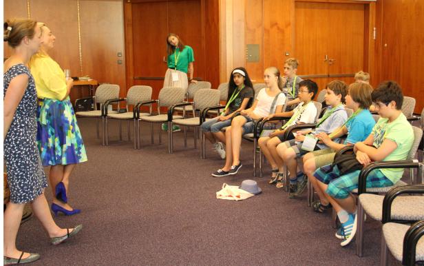 Eine Gruppe von Kindern sitzt in einem Raum und hört aufmerksam zu.