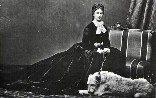 Kaiserin Elisabeth von Österreich sitzt mit ihrem Hund auf einem Stuhl.