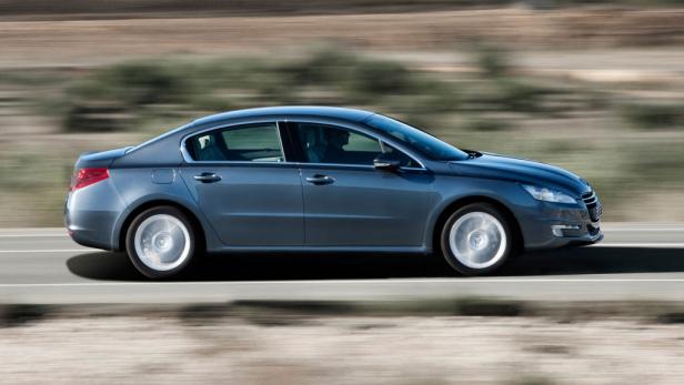 Ein blauer Peugeot 508 fährt auf einer Landstraße.