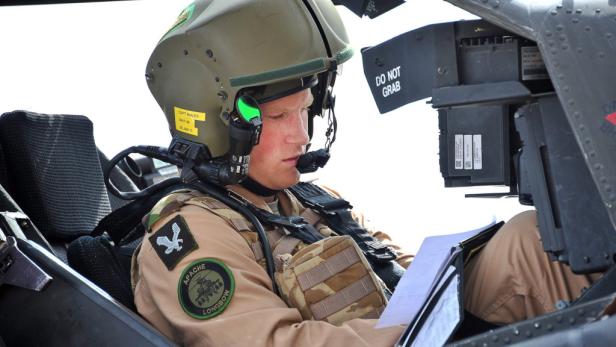 Prinz Harry im Cockpit eines Apache-Hubschraubers, während er Dokumente liest.