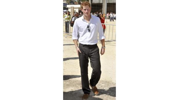 Prinz Harry geht im Hemd und dunkler Hose im Freien entlang.
