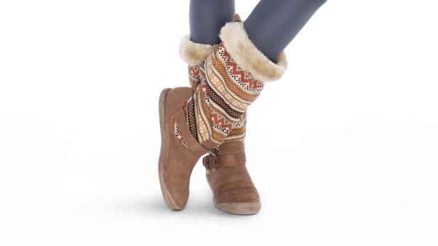 Beine in grauen Leggings und braunen Winterstiefeln mit Fellrand und Muster stehen auf einem weißen Hintergrund.