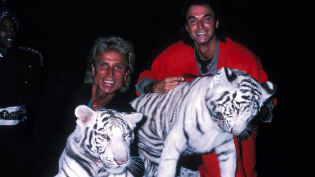 Siegfried und Roy posieren mit zwei weißen Tigern.