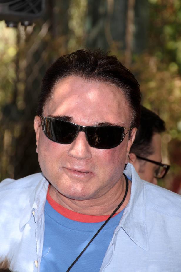 Ein Mann mit Sonnenbrille und blauem Hemd blickt in die Kamera.