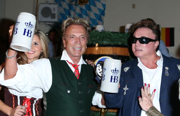 Zwei Männer in Tracht halten Bierkrüge der Marke Hofbräuhaus.