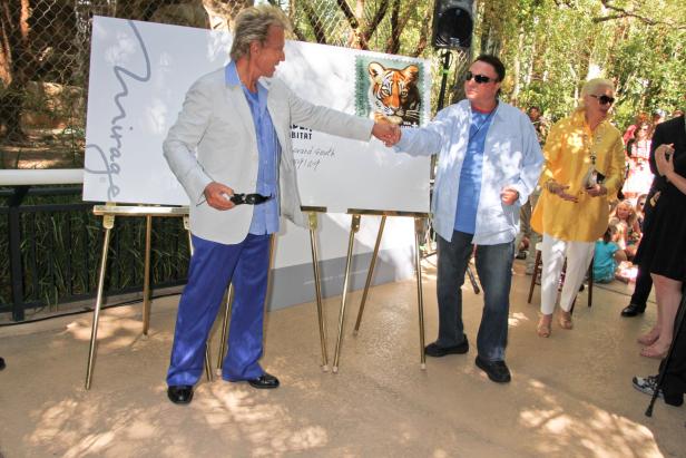 Siegfried Fischbacher und Roy Horn geben sich die Hand vor einem Schild des Mirage-Hotels.