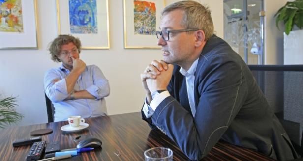 Zwei Männer sitzen an einem Tisch und unterhalten sich.