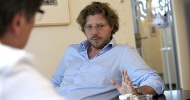 Ein Mann mit Brille gestikuliert während eines Gesprächs.