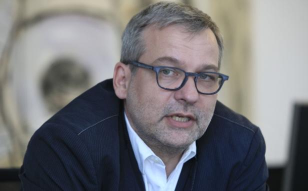 Ein Mann mit Brille und Anzug spricht.