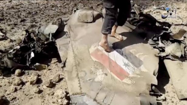 Eine Person steht barfuß auf einem Trümmerteil mit einer aufgemalten Flagge.