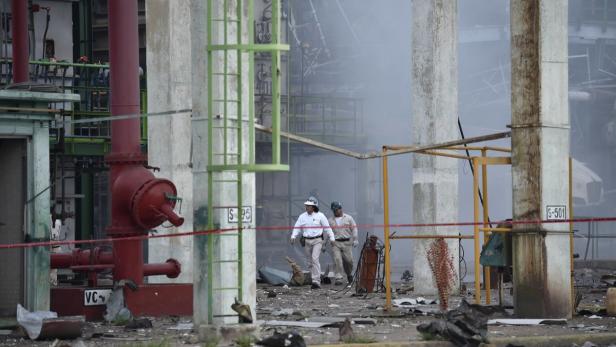 Zwei Arbeiter inspizieren die Schäden an einer Industrieanlage nach einer Explosion.