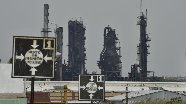 Eine Industrieanlage mit mehreren Schornsteinen und Hinweisschildern für einen internen Treffpunkt.