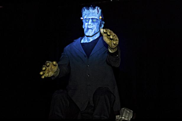 Eine blau beleuchtete Frankenstein-Figur mit ausgestreckten Händen.