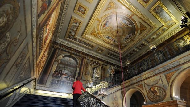 Eine Frau geht die Treppe in einem reich verzierten Gebäude hinauf.