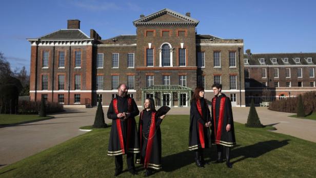 Vier Personen in historischen Kostümen stehen vor dem Kensington Palace.
