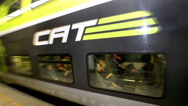 Ein CAT-Zug mit Fahrgästen an Bord steht am Bahnsteig.