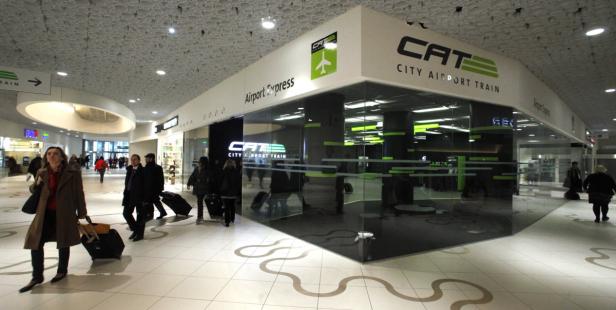 Reisende passieren den CAT City Airport Train am Flughafen Wien.