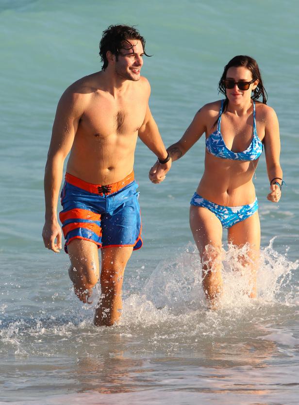 Ein Paar läuft Hand in Hand durch das flache Wasser am Strand.