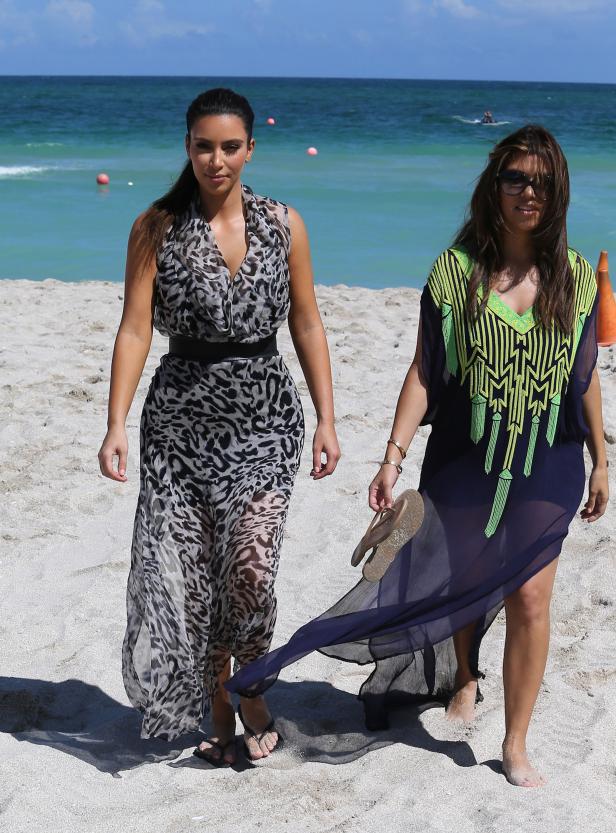 Kim und Kourtney Kardashian spazieren am Strand entlang.