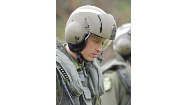 Ein Mann in olivgrüner Pilotenuniform und Helm mit Visier.