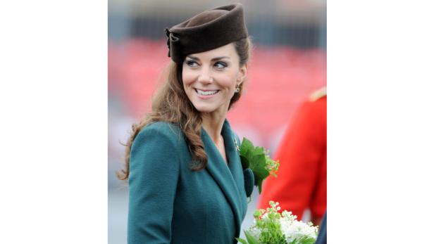 Kate Middleton mit einem braunen Hut und einem Blumenstrauß.