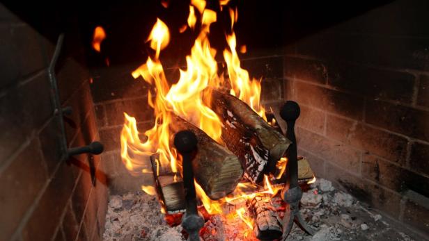 Ein Kaminfeuer brennt mit hellen Flammen und glühenden Holzscheiten.