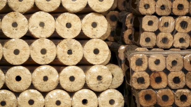 Gestapelte, in Folie verpackte Holzbriketts mit Loch in der Mitte.