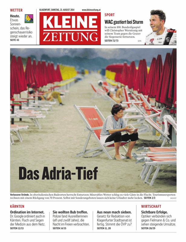 Eine Frau liest ein Buch an einem verlassenen Strand mit roten Sonnenschirmen.