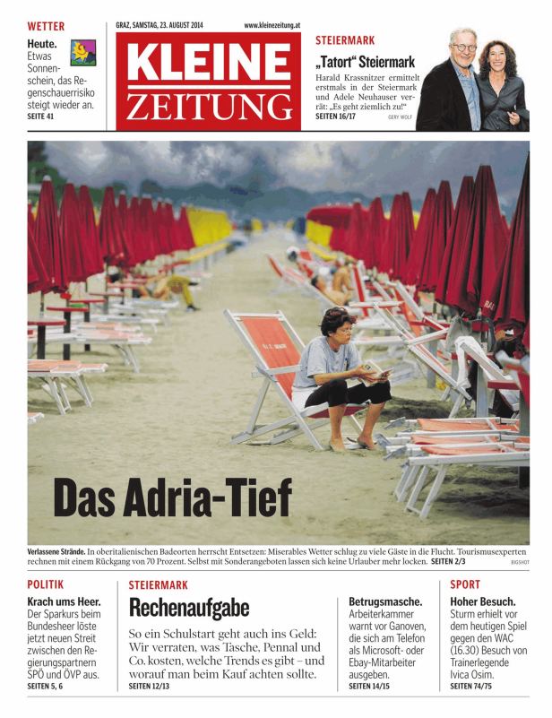 Eine Frau liest ein Buch an einem verlassenen Strand mit roten Sonnenschirmen.