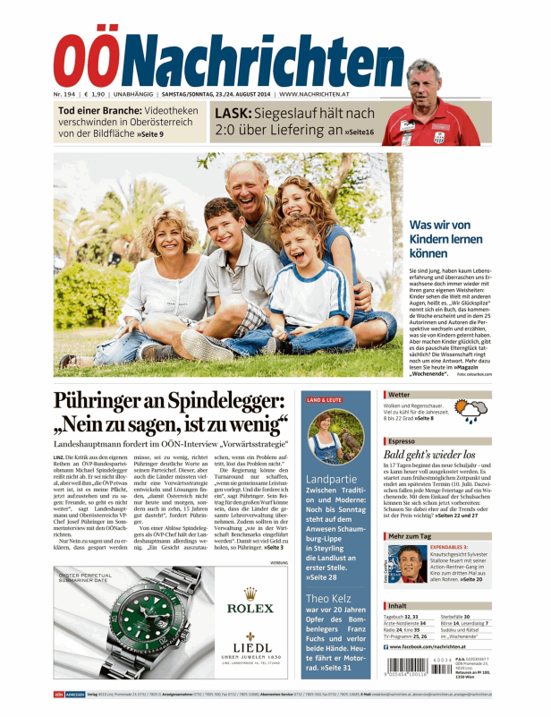 Eine lächelnde Familie sitzt im Freien auf einer Wiese.