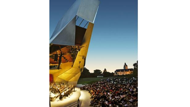 Ein Orchester spielt vor einem großen Publikum im Open-Air-Theater Grafenegg.